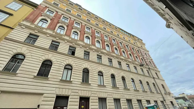 Historisches Gebäude mit klassischer Fassade und großen Fenstern an einer städtischen Straße.