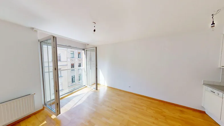 Helles Wohnzimmer mit Parkettboden, weißen Wänden und Zugang zu einem französischen Balkon.