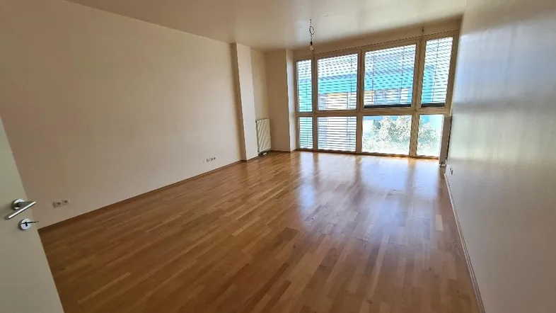 Helles Wohnzimmer mit Parkettboden, großen Fenstern und viel natürlichem Licht.
