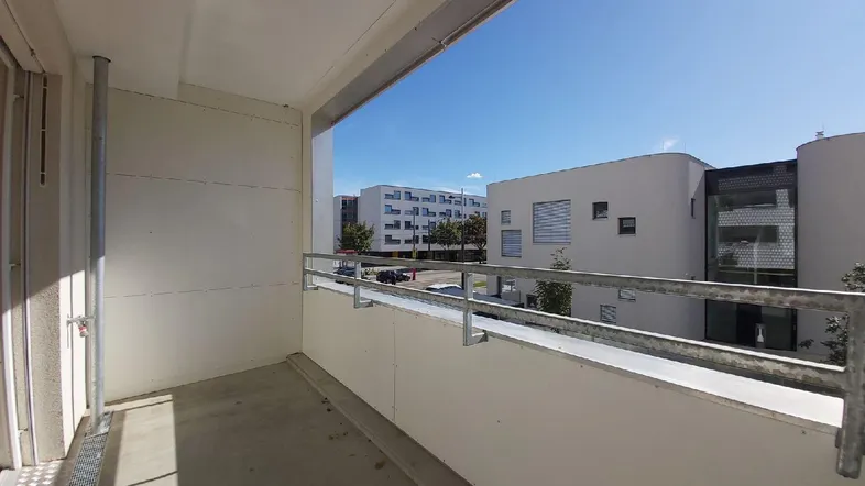 Heller Balkon mit Metallgeländer und Blick auf die umliegenden Gebäude.