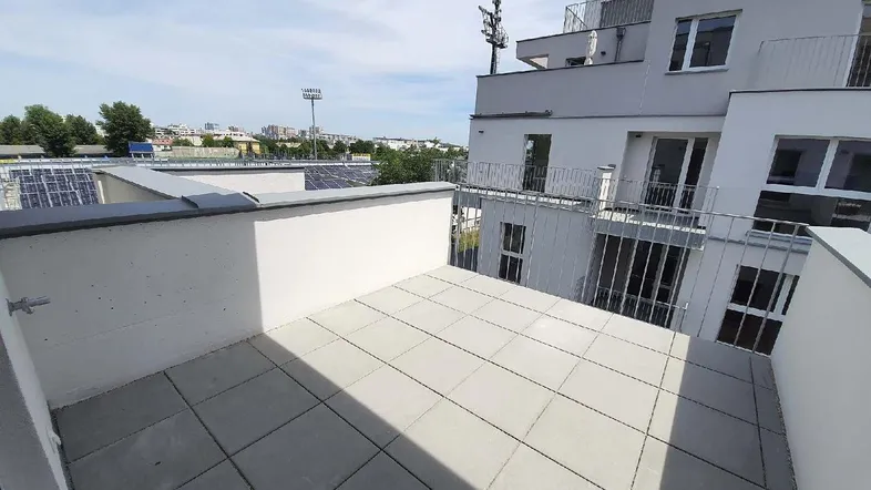 Leere Dachterrasse mit hellen Fliesen und Blick auf die städtische Umgebung.