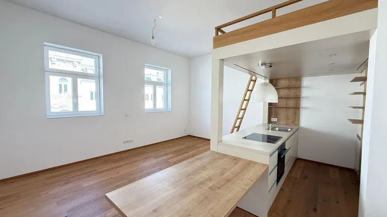 Helles Wohnzimmer mit integrierter Küchenzeile, Holzboden und Hochbett in einem modernen Ambiente.