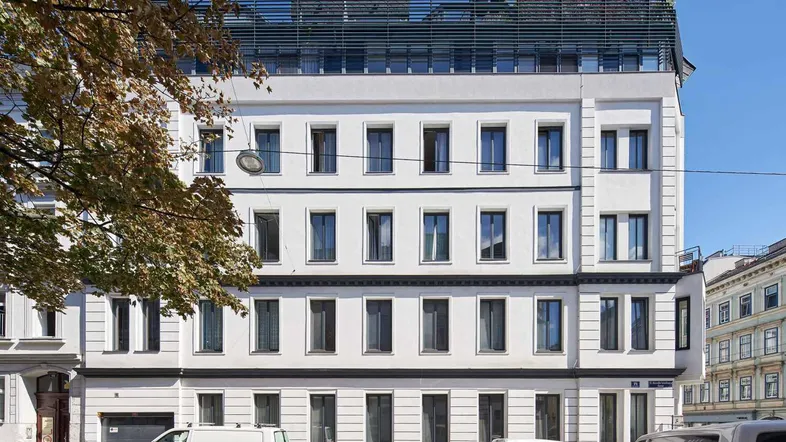 Frontansicht eines modernen Wohngebäudes mit vielen Fenstern und einem Dachaufbau.