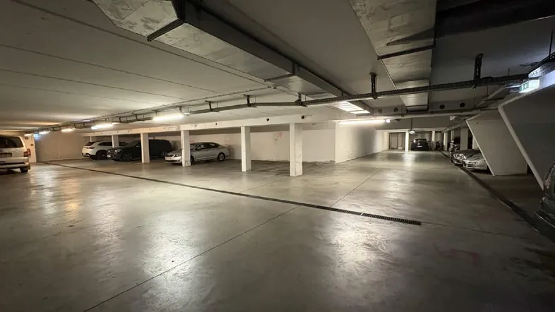 Geräumige Tiefgarage mit Betonboden und sichtbaren Installationen, bietet mehrere Stellplätze.