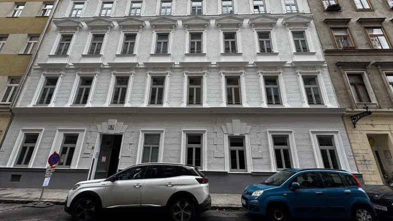 Klassische Fassade eines Mehrfamilienhauses in gutem Zustand mit vielen Fenstern.