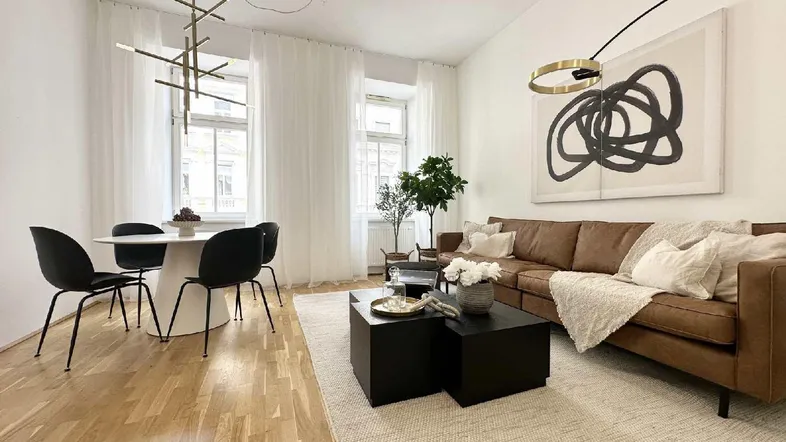 Heller Wohn- und Essbereich mit modernem Design, Holzboden und großen Fenstern, die viel Tageslicht hereinlassen.
