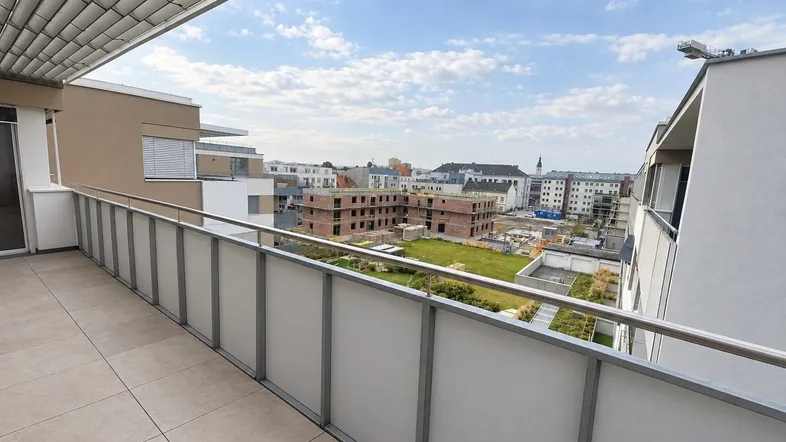 Geräumiger Balkon mit Fliesenboden und Blick auf die umliegende Bebauung und Baustelle.
