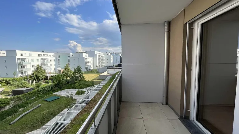 Geräumiger Balkon mit Fliesenboden und Blick auf die umliegenden Wohngebäude und Grünflächen.