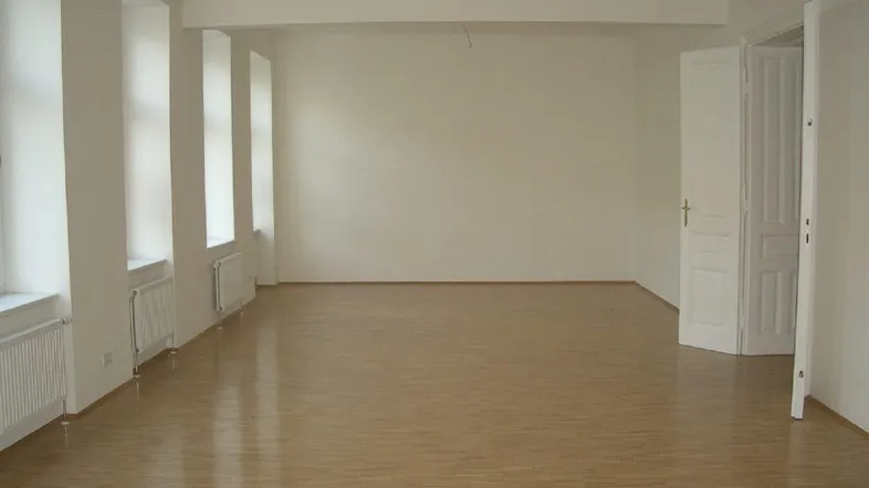 Heller, leerer Raum mit Parkettboden und mehreren Fenstern, bereit zur individuellen Gestaltung.
