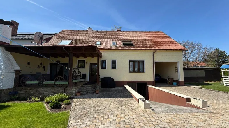 Ansicht des Hauses von außen mit gepflasterter Einfahrt, Garage und überdachtem Bereich.