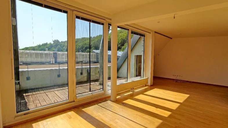 Helles Zimmer mit Holzboden und Zugang zu einer sonnigen Terrasse, ideal als Wohnbereich.