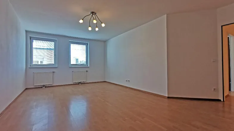 Helles, leeres Wohnzimmer mit Parkettboden und zwei Fenstern, bereit zur individuellen Gestaltung.