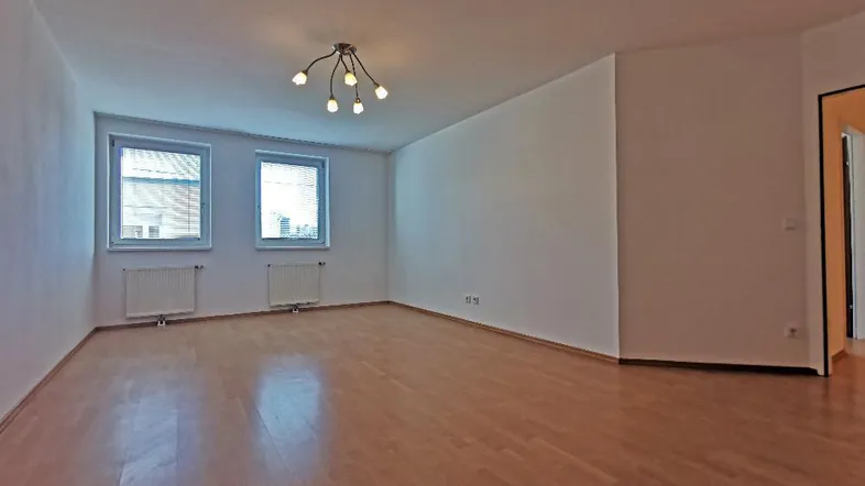 Helles, leeres Wohnzimmer mit Parkettboden und zwei Fenstern, bereit zur individuellen Gestaltung.