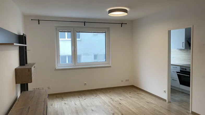 Helles Zimmer mit Holzfußboden und Blick in die angrenzende Küche, ideal als Wohnbereich.