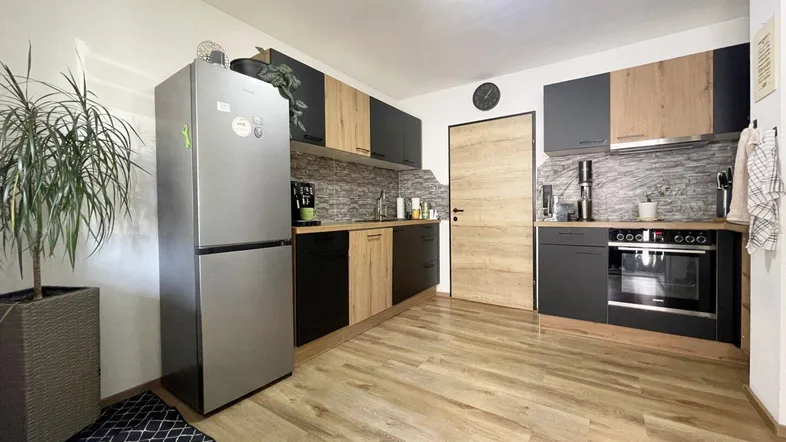 Moderne Küche mit Holz- und Anthrazitfronten, ausgestattet mit Kühlschrank und Backofen.