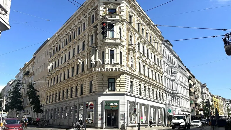 Historisches Eckgebäude mit reich verzierter Fassade an einer belebten Stadtkreuzung.