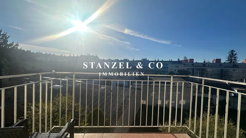 Sonniger Balkon mit Fliesenboden und Blick auf die umliegenden Gebäude und Bäume.