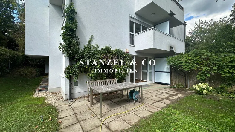 Große gepflasterte Terrasse mit Gartenmöbeln und Zugang zum grünen Gartenbereich des Hauses.