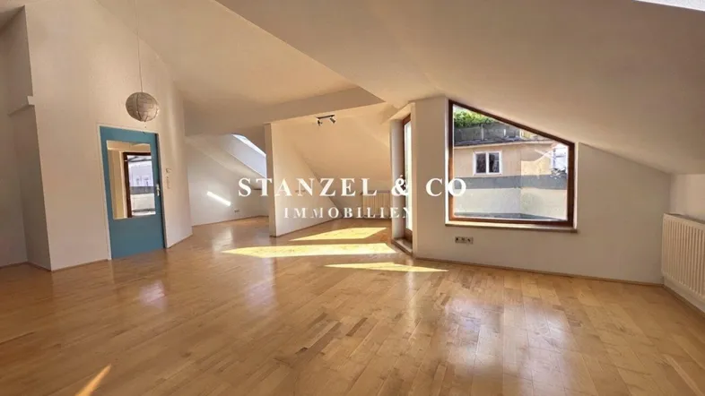 Helles Dachgeschoss-Wohnzimmer mit Holzboden, schrägen Wänden und viel natürlichem Licht.