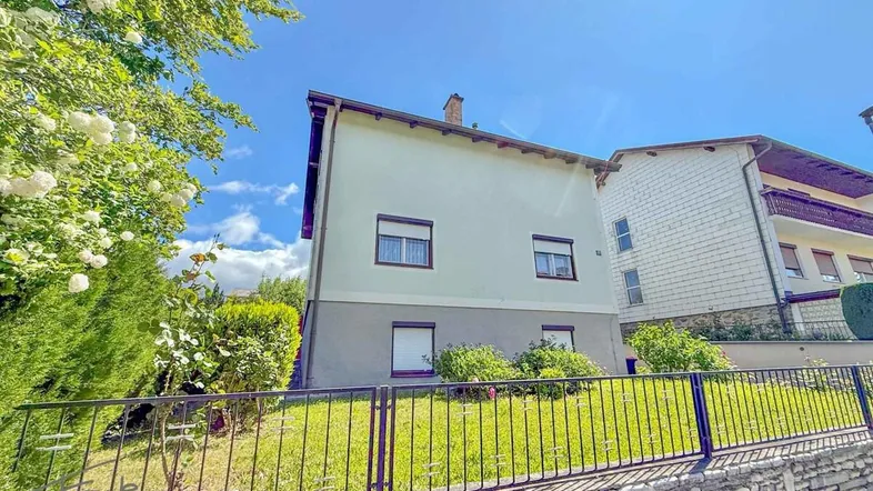 Einfamilienhaus mit gepflegtem Vorgarten und sonnigem Himmel an einem klaren Tag.