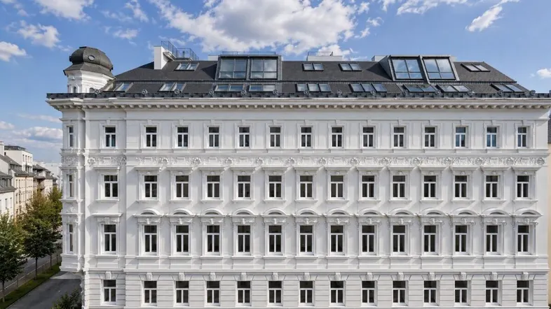 Elegante weiße Fassade eines historischen Gebäudes mit modernen Dachfenstern und vielen Details.