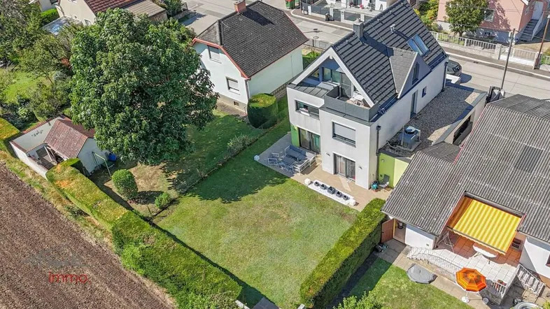 Luftaufnahme des modernen Hauses mit großem Garten und angrenzendem Feld.
