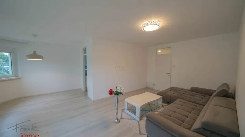 Helles Wohnzimmer mit modernem Laminatboden und einer gemütlichen Sitzecke.