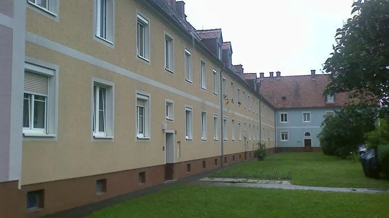 Mehrere Wohngebäude mit gelber Fassade und einem grünen Innenhof mit Rasenfläche.