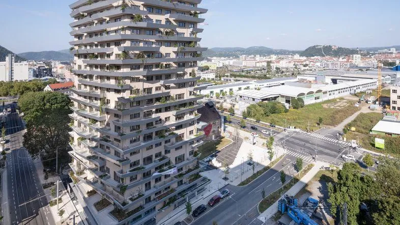 Luftaufnahme eines modernen Hochhauses mit vielen Balkonen in einer städtischen Umgebung.