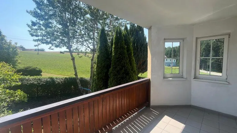 Geräumiger Balkon mit Fliesenboden und Holzbalkonbrüstung, bietet einen weiten Blick ins Grüne.