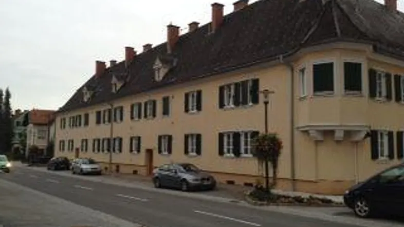 Historisches Gebäude mit mehreren Fenstern und einem Erker an einer ruhigen Straße.