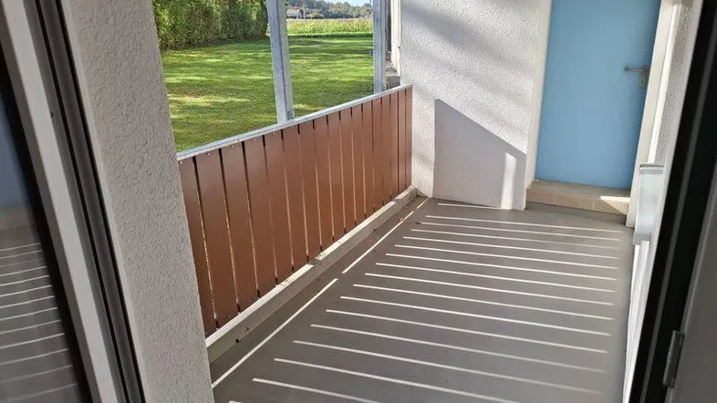 Heller Balkon mit Holzelementen und Blick ins Grüne, ideal zum Entspannen.