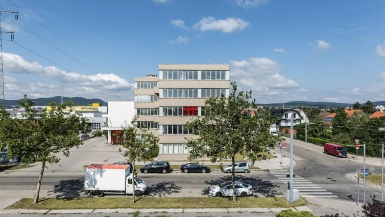 Ansicht des modernen Bürogebäudes von oben mit umliegender Straße, Parkplätzen und Industriegebiet im Hintergrund.