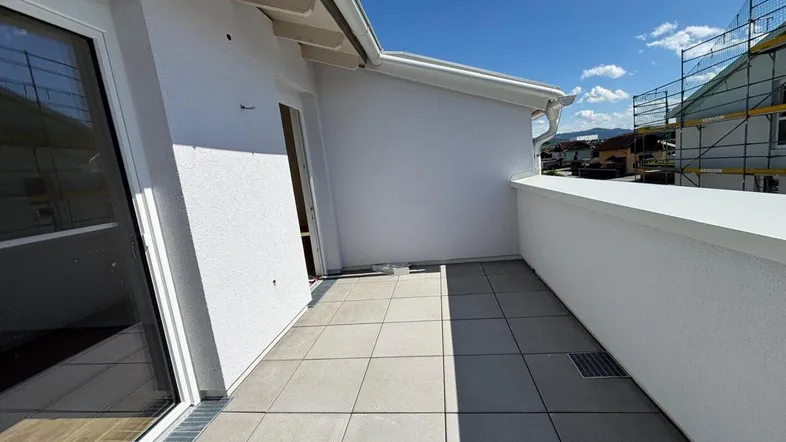 Heller Balkon mit Fliesenboden und Blick auf die Umgebung, ideal für entspannte Stunden im Freien.
