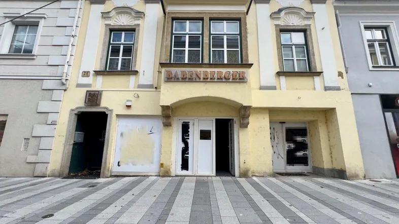 Historische Fassade eines Gebäudes mit Schaufenstern und Eingangsbereich an einer Straße.