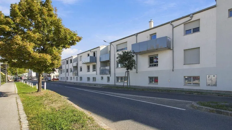 Moderne Wohnanlage mit Balkonen entlang einer ruhigen Straße.