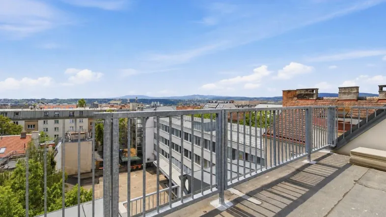 Große Dachterrasse mit Metallgeländer und weitem Blick über die Stadt und die umliegenden Hügel.