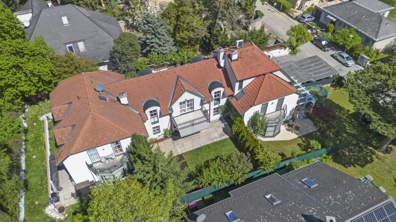 Drohnenaufnahme eines Hauses mit rotem Ziegeldach und umliegendem Garten in einer Wohngegend.