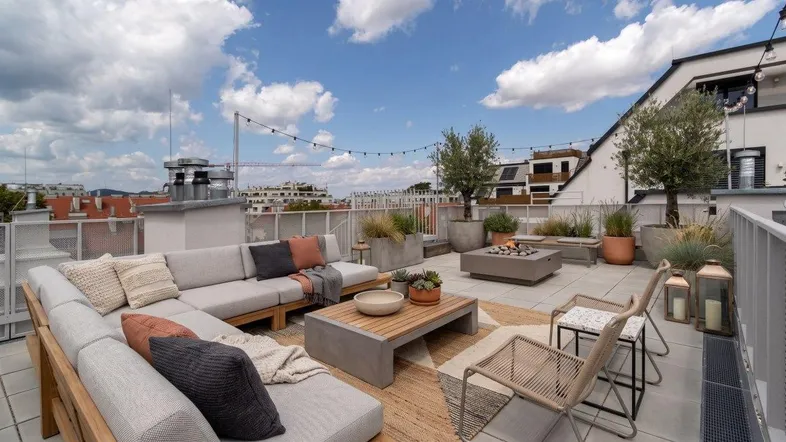Geräumige Dachterrasse mit bequemen Loungemöbeln, Feuerstelle und weitem Stadtblick.