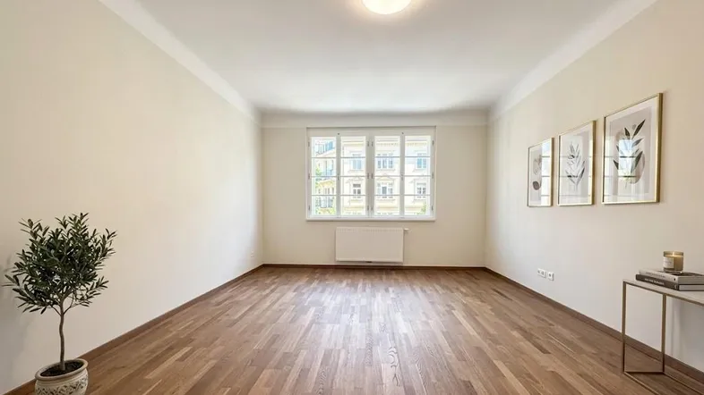 Helles Zimmer mit Parkettboden, großen Fenstern und schlichten Wänden.
