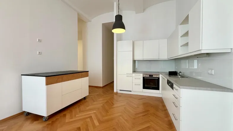 Moderne Küche mit weißen Schränken, integrierten Geräten und elegantem Fischgrätparkettboden.