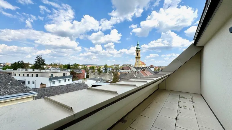 Geräumige Terrasse mit Fliesenboden und weitem Blick über die Stadt mit Kirchturm.