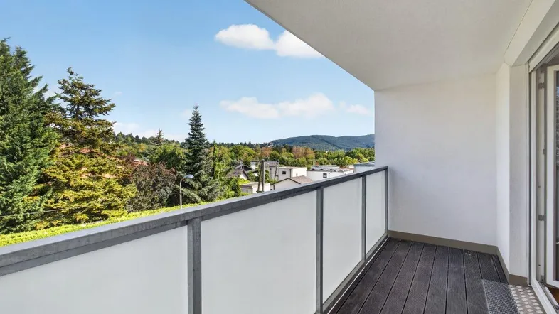 Geräumiger Balkon mit Holzboden und Blick ins Grüne sowie auf die umliegende Landschaft.