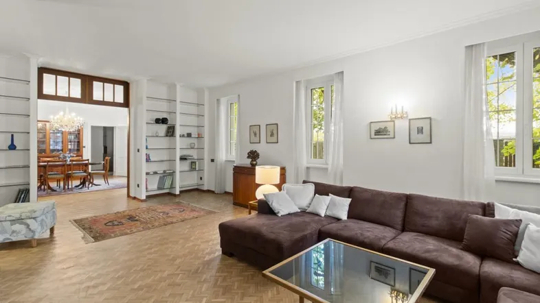 Helles Wohnzimmer mit Parkettboden, großem Sofa und Blick in den Essbereich.