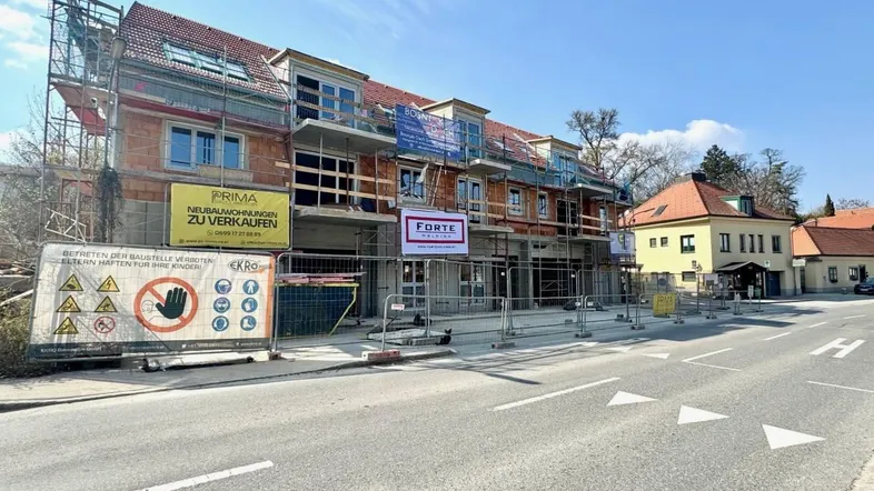 Neubauprojekt in Bauphase mit Gerüsten und Werbebannern an der Hauptstraße.