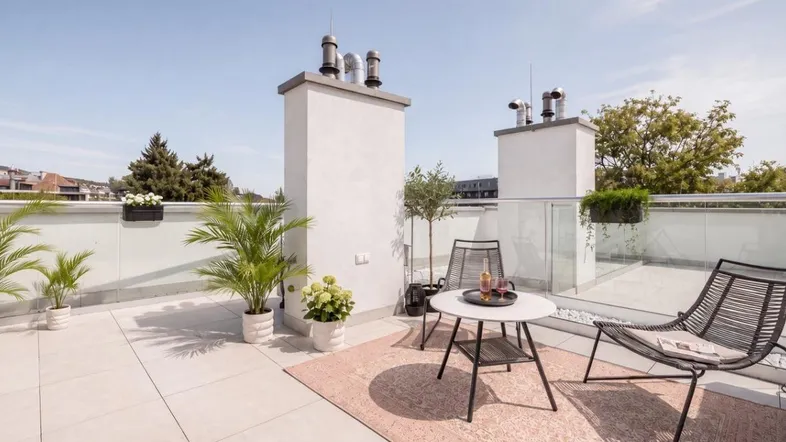 Geräumige Dachterrasse mit modernen Gartenmöbeln, Pflanzen und weitem Blick über die Umgebung.