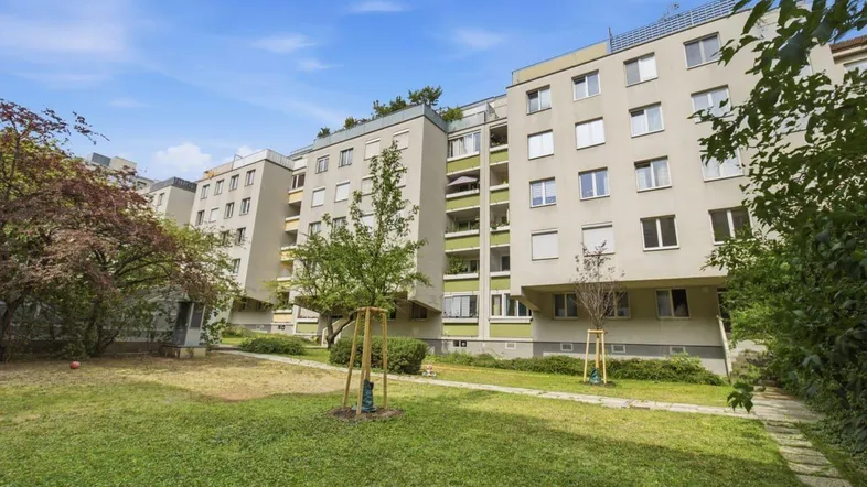 Mehrfamilienhaus mit gepflegter Grünanlage und Bäumen, die zum Entspannen einlädt.