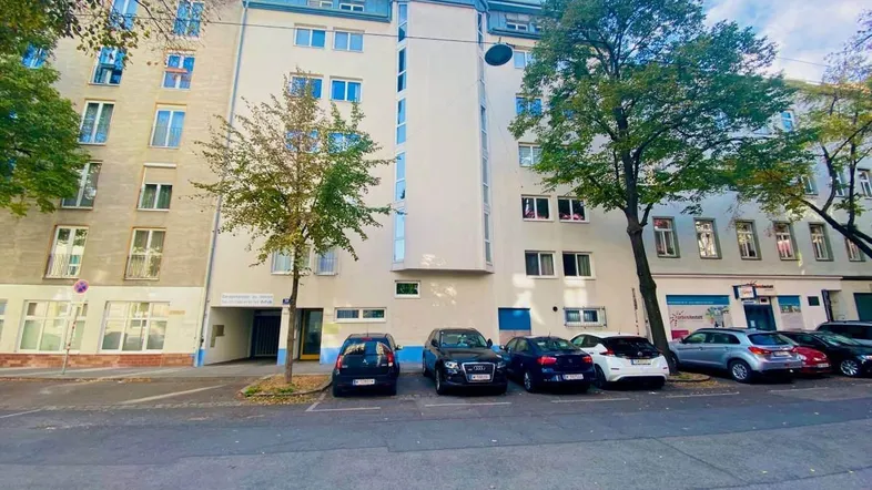 Fassade eines Wohngebäudes mit geparkten Autos auf der Straße.