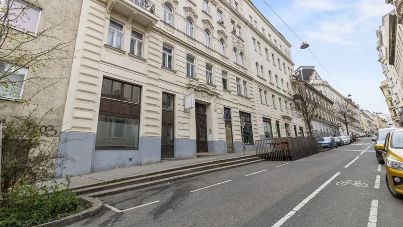 Historisches Gebäude mit klassischer Fassade und Balkonen an einer belebten Stadtstraße.
