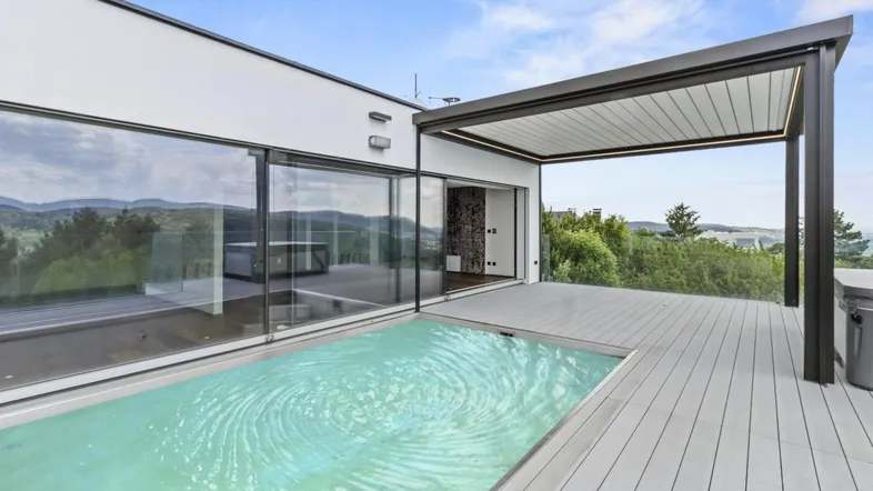 Moderne Terrasse mit integriertem Pool, Pergola und weitem Blick ins Grüne.